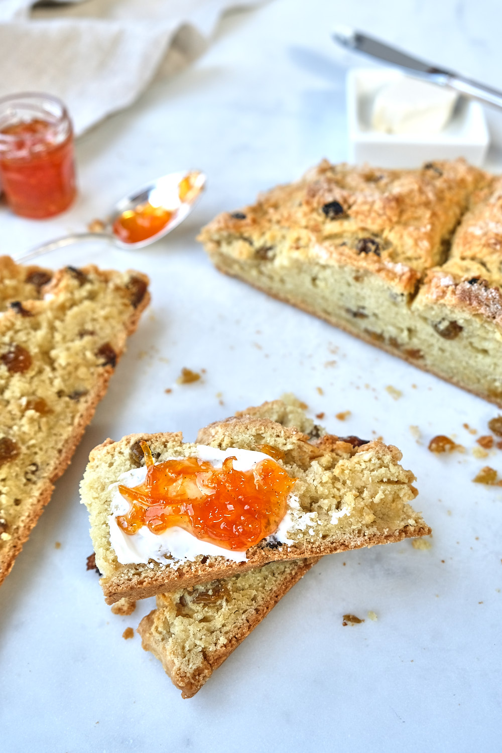 A loaf of irish soda bread cut into slices with orange marmalade. 