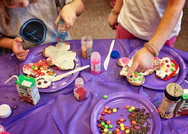Kids decorating gingerbread men with candy and frosting. 