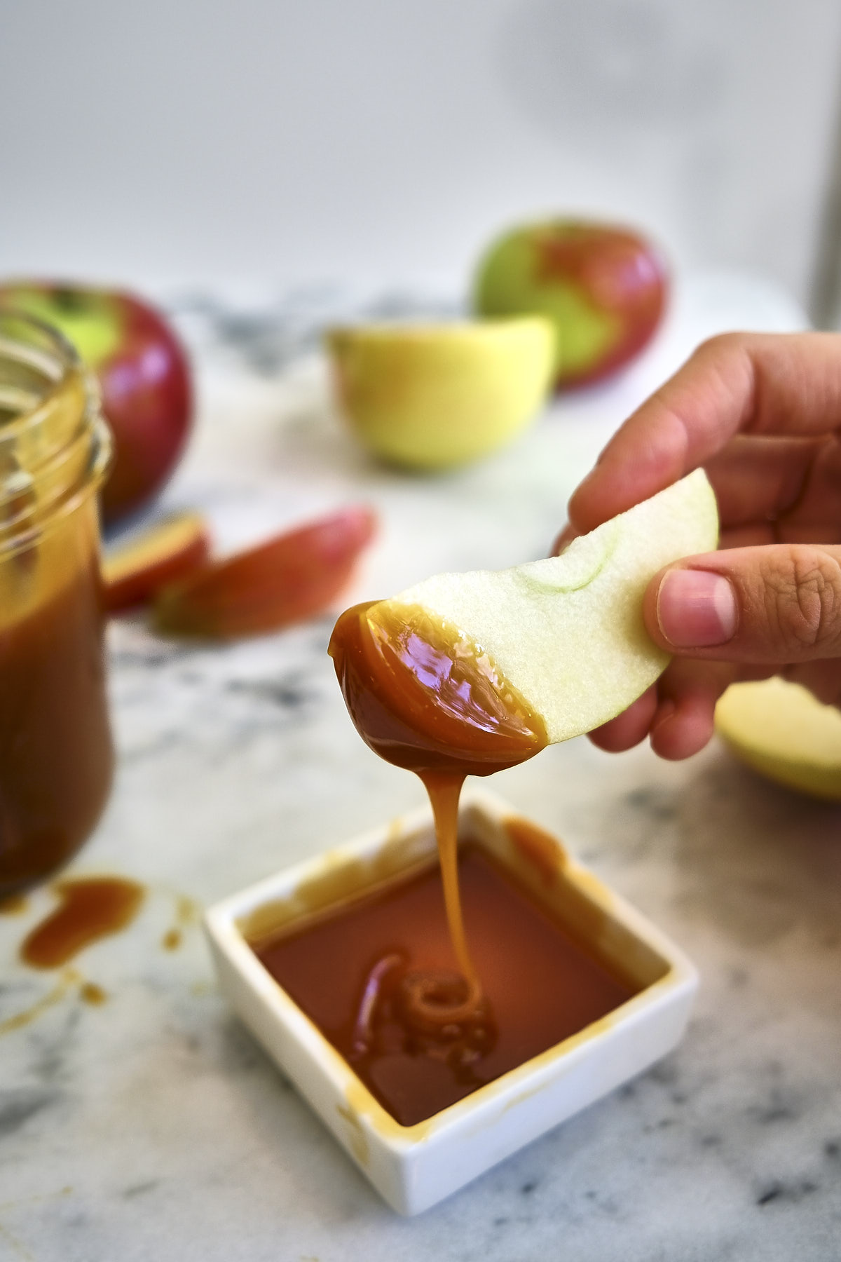 An apple slice dipped into dairy free caramel apple dip.